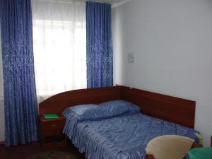 上沃洛乔克Hotel Berezka的一间卧室配有床和蓝色窗帘的窗户