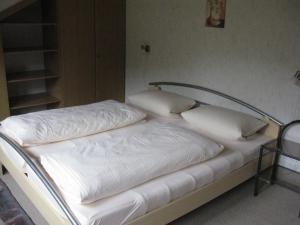 瓦门施泰纳赫Ferienwohnung Karlsruh的一张带白色床单和枕头的床