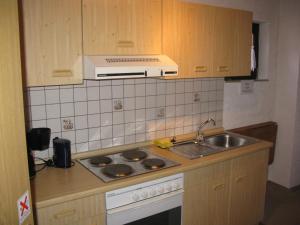 瓦门施泰纳赫Ferienwohnung Karlsruh的厨房配有水槽和炉灶 顶部烤箱