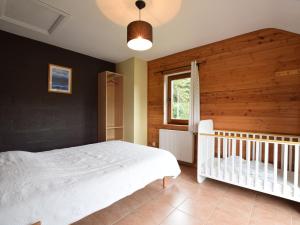 VerpréDuplex Chalet in Rendeux Ardennes with Sauna and Terrace的卧室配有白色的床和婴儿床。