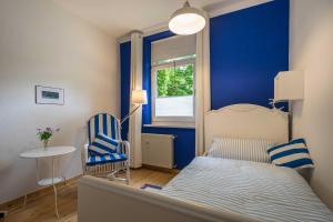 赛巴特班森Ferienwohnungen Proll的卧室拥有蓝色的墙壁,配有一张床和椅子
