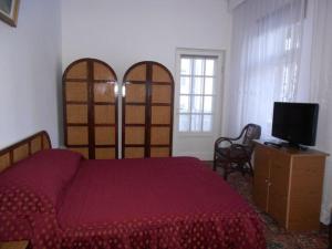 锡纳亚谭茨酒店的一间卧室配有红色的床和电视