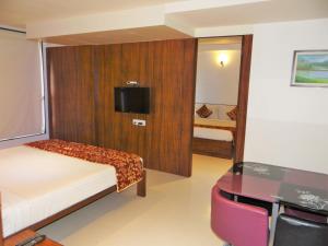 舍地寺庙景观酒店的一间卧室配有一张床、一张书桌和一台电视。