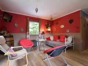 胡法利兹Chalet in a green and peaceful environment的客厅设有红色的墙壁、沙发和椅子