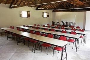 伊塔比里图Hotel Fazenda Caco de Cuia的配有桌椅和红色椅子的房间