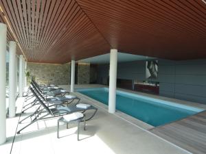 马尔梅迪Rich Holiday Home in Malmedy with Indoor Heated Pool的一座带躺椅的游泳池位于大楼旁