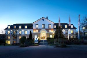 黑尔姆施泰特Best Western Hotel Helmstedt am Lappwald的一座白色的大建筑,灯火通明