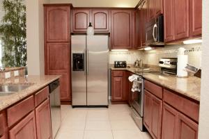 奥兰多Cayview Condo #231543的厨房配有木制橱柜和不锈钢冰箱。