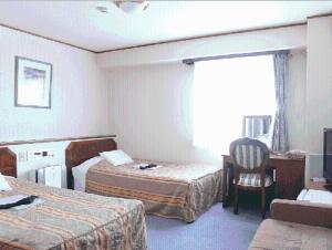 新泻站前艺术酒店的酒店客房,配有两张床和椅子