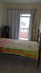 皮乌马Apartamento em Piúma-ES的一间卧室设有一张床和一个大窗户