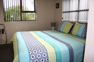 提马鲁阿什伯里公园汽车旅馆的一间卧室配有一张带蓝色毯子的床和两个窗户。