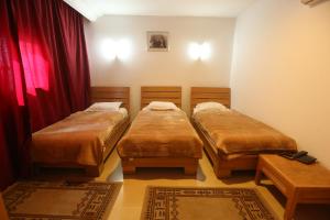 斯法克斯娜谢艾尔芳瑙酒店的宿舍间内的两张床,配有红色窗帘和地毯