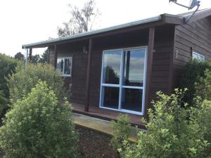 WetheralKairaki Beach Motor Camp的小木屋设有大窗户和灌木丛