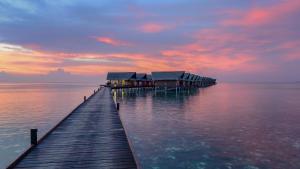 北马累环礁Adaaran Select Huduran Fushi - with 24hrs Premium All Inclusive的日落时分水面上房屋的码头