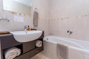 戈登湾蓝色地平线宾馆的浴室配有白色水槽和浴缸。