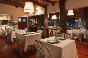 科洛尼亚卡洛斯佩莱格里尼南德丽德旅馆的餐厅设有白色的桌椅和窗户。