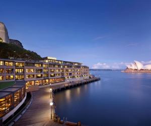 悉尼悉尼柏悦酒店的一座在夜间水面上灯亮的大建筑