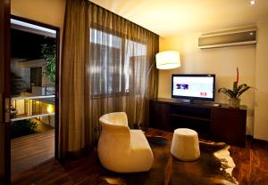 危地马拉拉因马库拉达酒店的客厅配有两把白色椅子和电视