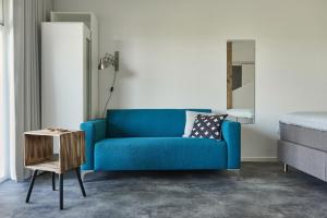 格罗宁根B&B Molenstreek的一张蓝色的沙发,位于一个配有一张床和一张桌子的房间