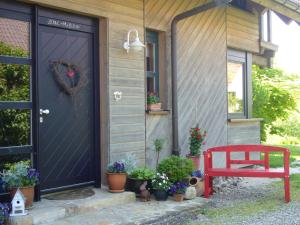 沙尔施塔特Silvia Krafts Bed and Breakfast的一座有盆栽植物和红色长凳的房子的门