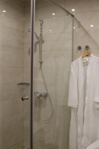 阿德勒扎拉酒店的配有白色浴袍和淋浴的浴室