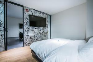 大邱河畔酒店的卧室配有白色的床和墙上的电视