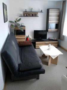 RathmannsdorfFerienwohnung Mey的客厅配有黑色真皮沙发和桌子
