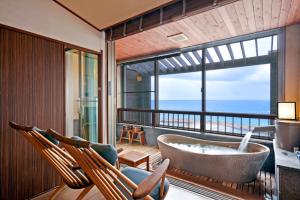 白滨三乐庄酒店的带浴缸的浴室和带椅子的阳台。