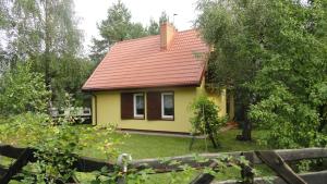 RybnoDomek nad jeziorem Rumian的红色屋顶的黄色小房子