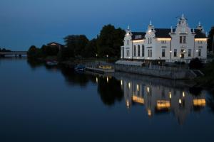 利耶帕亚Hotel Libava的一座白色的大建筑,晚上坐在水面上
