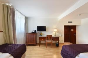 维也纳Hotel Am Schubertring的酒店客房设有书桌和卧室。