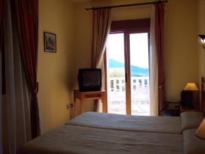 兰哈龙兰哈龙城堡酒店的一间卧室设有一张床、一台电视和一个窗口。