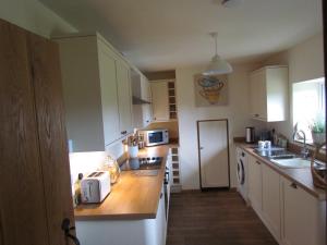 科尔温湾Cae Eithin的厨房配有白色橱柜和木制台面