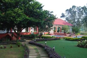 焦尔哈德Kaziranga Golf Resort的房屋前方设有花园,前面设有人行道