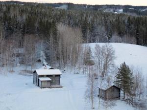 NorråkerMarjas stuga的两栋建筑,位于一片有树木的雪地中