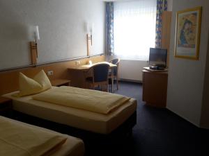 AlthengstettMotel Am Highway的酒店客房设有两张床、一张桌子和电视。