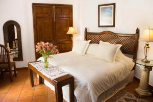 瓦哈卡市卡萨西耶特巴尔肯斯精品酒店的一间卧室配有一张床和一张鲜花桌子