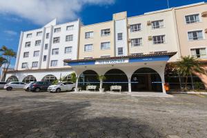 弗洛里亚诺波利斯Tri Hotel Florianópolis的一座白色的大建筑,汽车停在停车场
