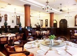 泗水Hotel Majapahit Surabaya MGallery的用餐室配有桌椅和吊灯。
