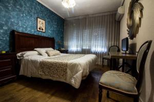萨拉曼卡Hostal Goya Suites的一间卧室配有一张床、一张桌子和一台电视。