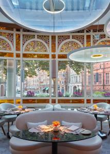 伦敦梅宝尼康诺酒店的餐厅设有桌椅和大窗户。