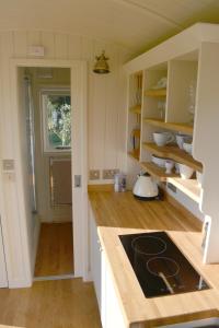 托特尼斯Kerswell Farm Shepherd Huts的厨房配有白色橱柜和炉灶烤箱。