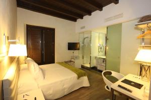 阿尔卡拉德荷那利斯伊万尼亚阿尔卡拉精品酒店的酒店客房配有一张床、一张书桌和一台电视。