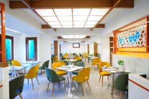 罗希姆诺Atrium Ambiance Hotel的用餐室配有桌子和黄色椅子