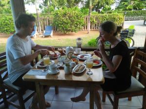 拉迪格岛克里奥尔木屋的坐在餐桌旁吃食物的男人和女人