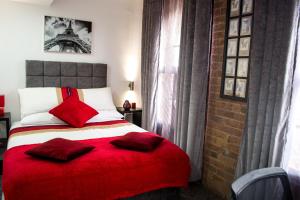 诺丁汉诺丁汉特里维尔斯摄政酒店的一间卧室配有一张带红色毯子的床