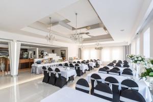 克拉科夫朱尼尔酒店的宴会厅配有白色桌子和黑色椅子