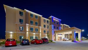 布达Best Western Plus Buda Austin Inn & Suites的停车场内有车辆的旅馆