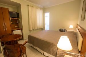 索罗卡巴索罗卡巴伊帕内玛酒店的一间卧室配有一张床、一张桌子和一盏灯