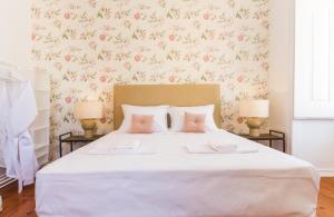 里斯本领城市阁楼里旅馆的卧室配有带粉红色花卉的大型白色床